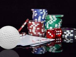 Golfball, Spielkarten und Pokerchips liegen auf einem Tisch