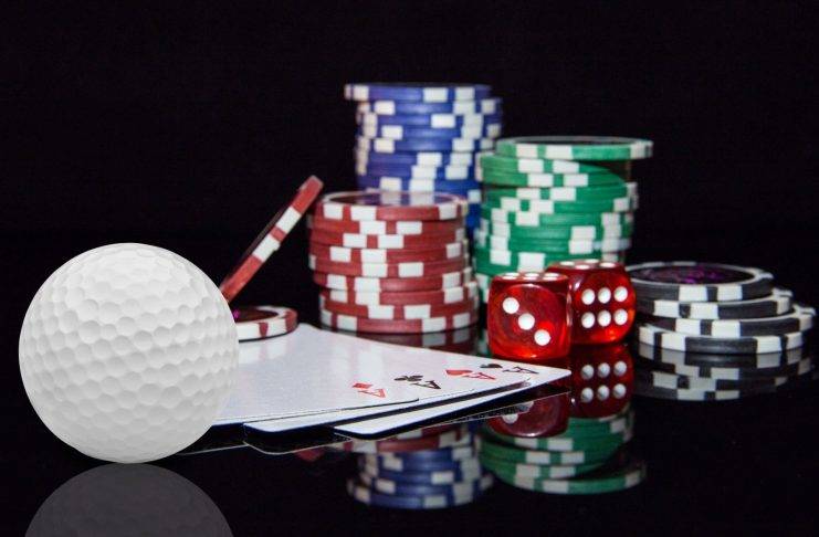 Golfball, Spielkarten und Pokerchips liegen auf einem Tisch