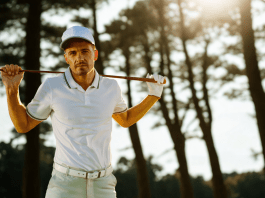 Golfer mit Golfschläger steht vor einem schattigen Wald