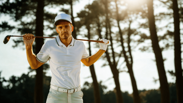 Golfer mit Golfschläger steht vor einem schattigen Wald
