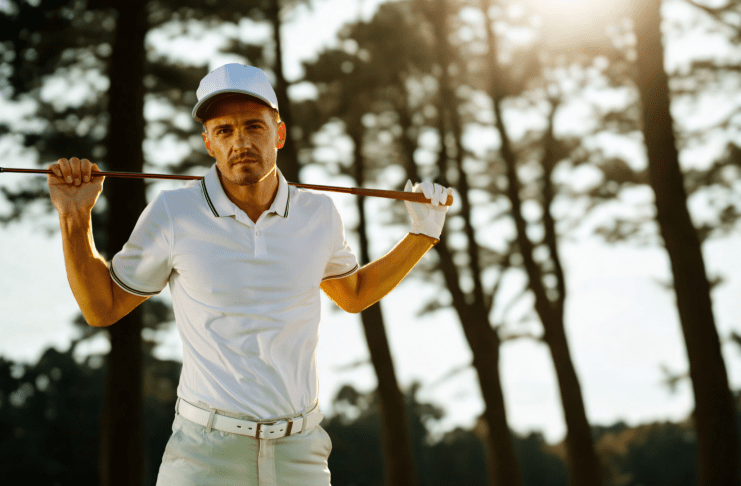 Golfer mit Golfschläger steht vor einem schattigen Wald