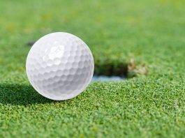 Golfball liegt neben dem Loch auf dem Green