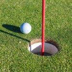 Spiel mit System: Besseres Golf spielen durch kluge Planung Golfball liegt neben dem Loch auf dem Grün