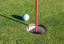 Spiel mit System: Besseres Golf spielen durch kluge Planung Golfball liegt neben dem Loch auf dem Grün