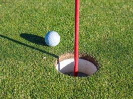 Spiel mit System: Besseres Golf spielen durch kluge Planung Golfball liegt neben dem Loch auf dem Grün