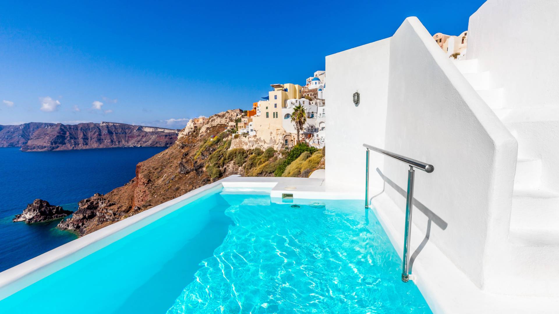 Großer Pool mit Blick auf das Meer vor einem weißen Hotel